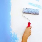 Hand mit Malerrolle streicht die Wand